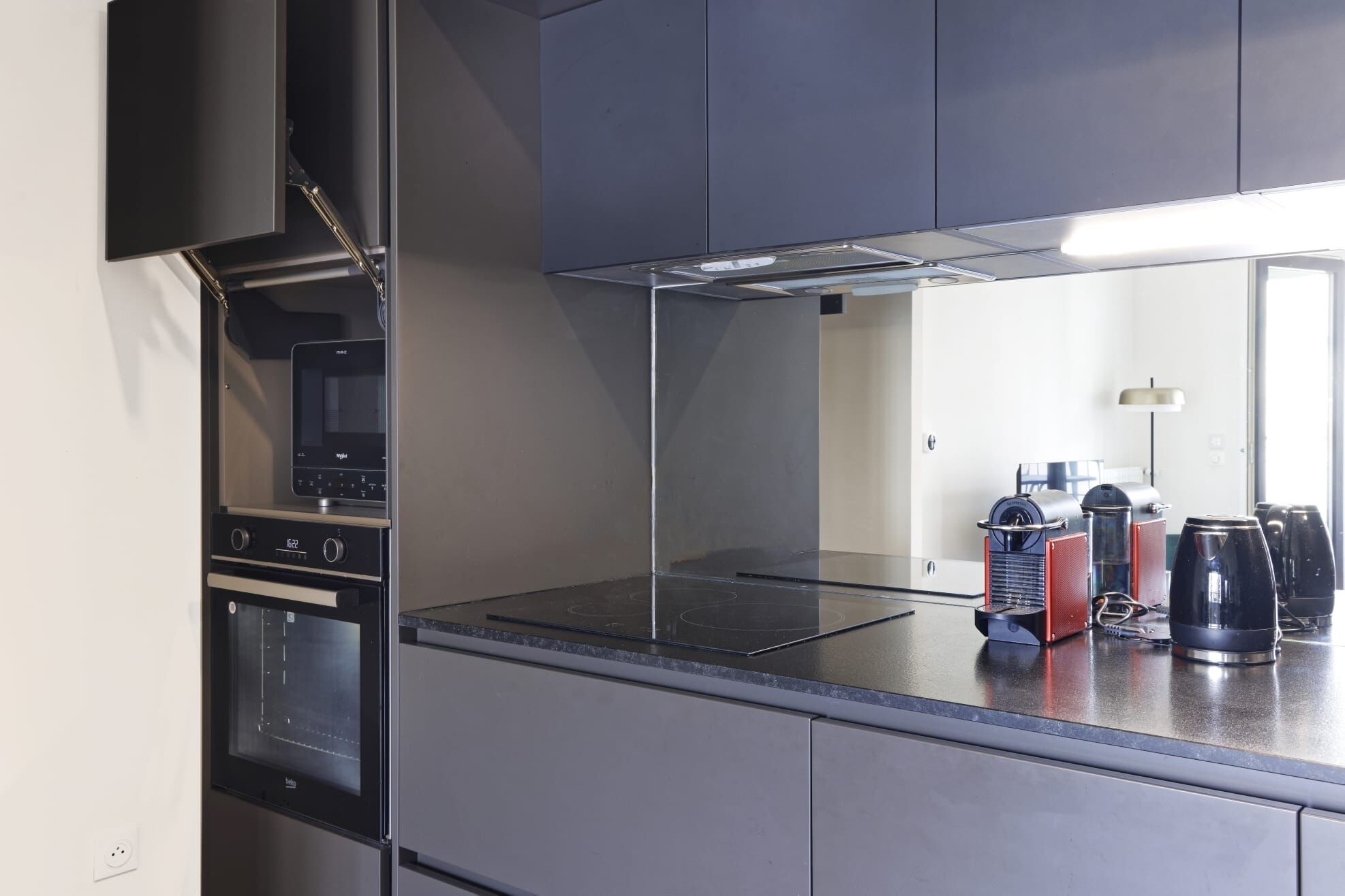 A modern kitchen with a built-in oven, microwave, and a stainless steel range hood.