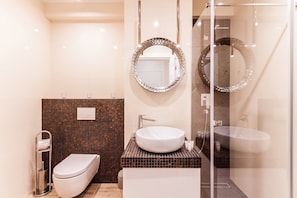 A modern bathroom with a white toilet, a sink with a mosaic tile backsplash, and two wall-mounted mirrors. - Inpoint Smart Apartments (Kraków)
