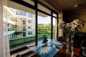 A modern hotel room with a balcony, a table with a blue patterned placemat, and a vase with white flowers. - Inpoint Smart Apartments (Kraków)