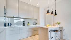 Una cocina moderna con armarios blancos, una isla de madera y taburetes de bar.