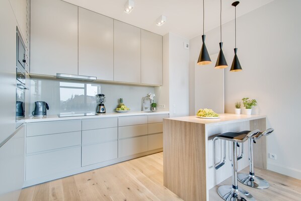 Une cuisine moderne avec des meubles blancs, un îlot central en bois et des tabourets de bar.