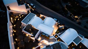 Vue aérienne d’un hôtel moderne doté de nombreuses suites, d’espaces de détente en plein air et d’une allée bien éclairée.