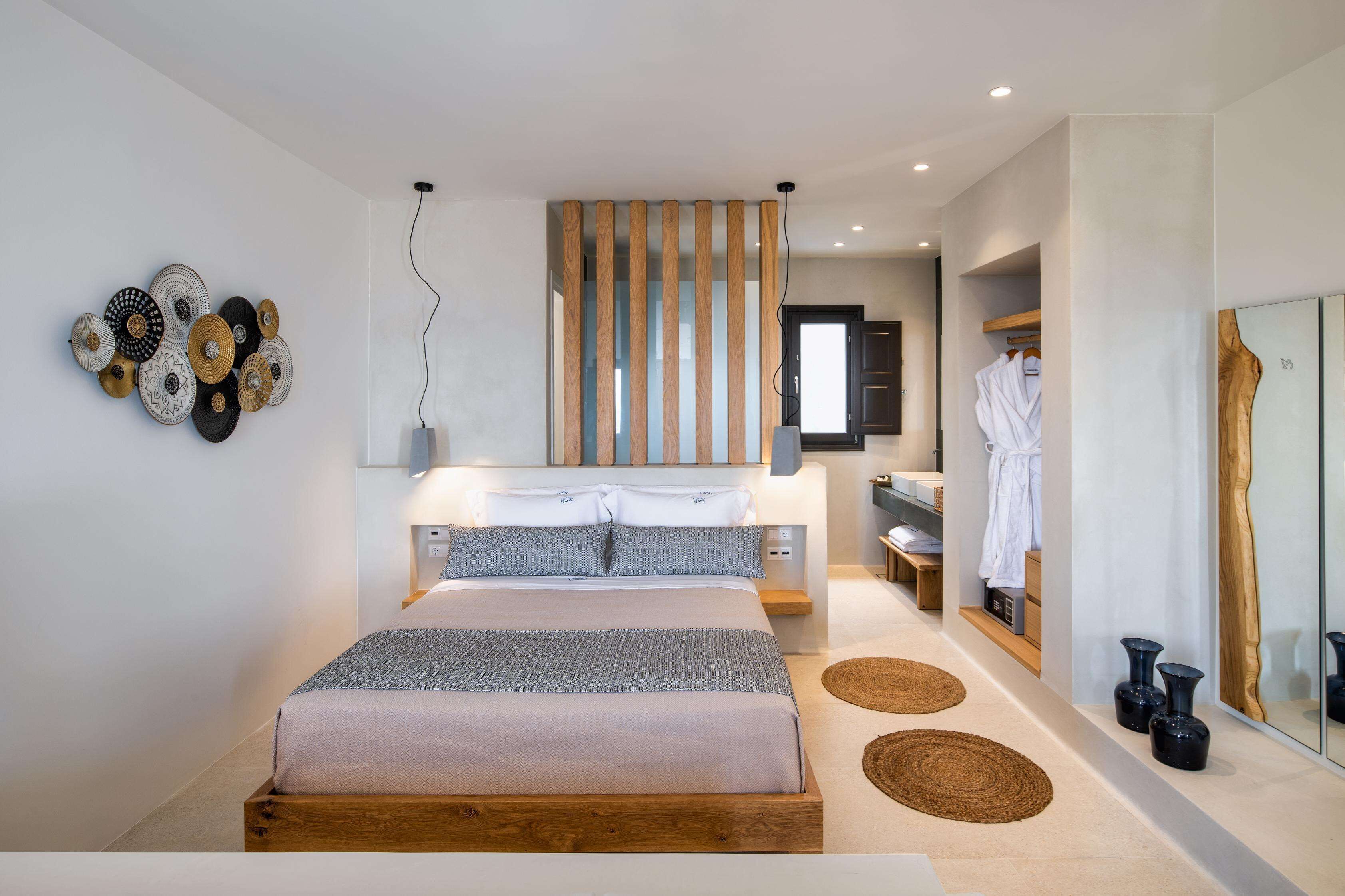 A modern bedroom with a large bed, bedside tables, a mirror, and a wooden partition.