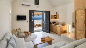 Un salon moderne avec un canapé, une table basse et un téléviseur. Il y a un coin cuisine avec des meubles en bois et un coin repas avec une table et des chaises.