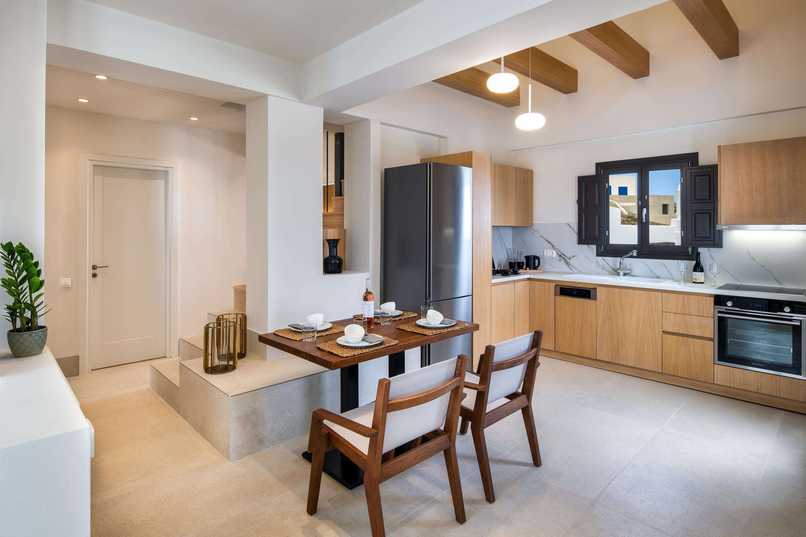 A modern kitchen with wooden cabinets, a stainless steel refrigerator, and a dining area with a table and chairs.