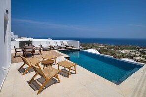 Un espace piscine aménagé sur le toit, avec des chaises longues et une vue sur la mer.