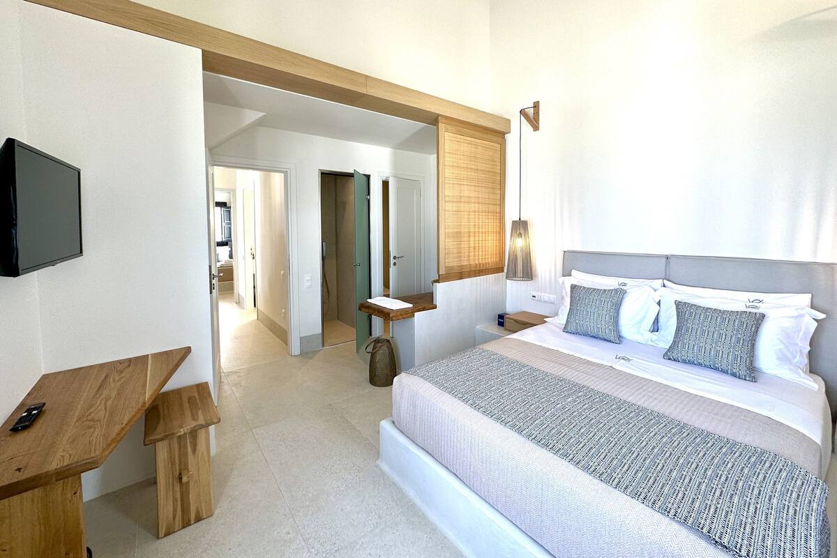 Een slaapkamer met een bed, nachtkastje en een aan de muur bevestigde televisie.