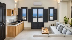 Un salon moderne avec un canapé, une table basse et une vue sur la mer, grâce à des portes ouvertes.