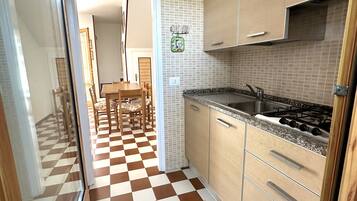 Køleskab, kogeplade, køkkentøj/tallerkener/redskaber, spisebord