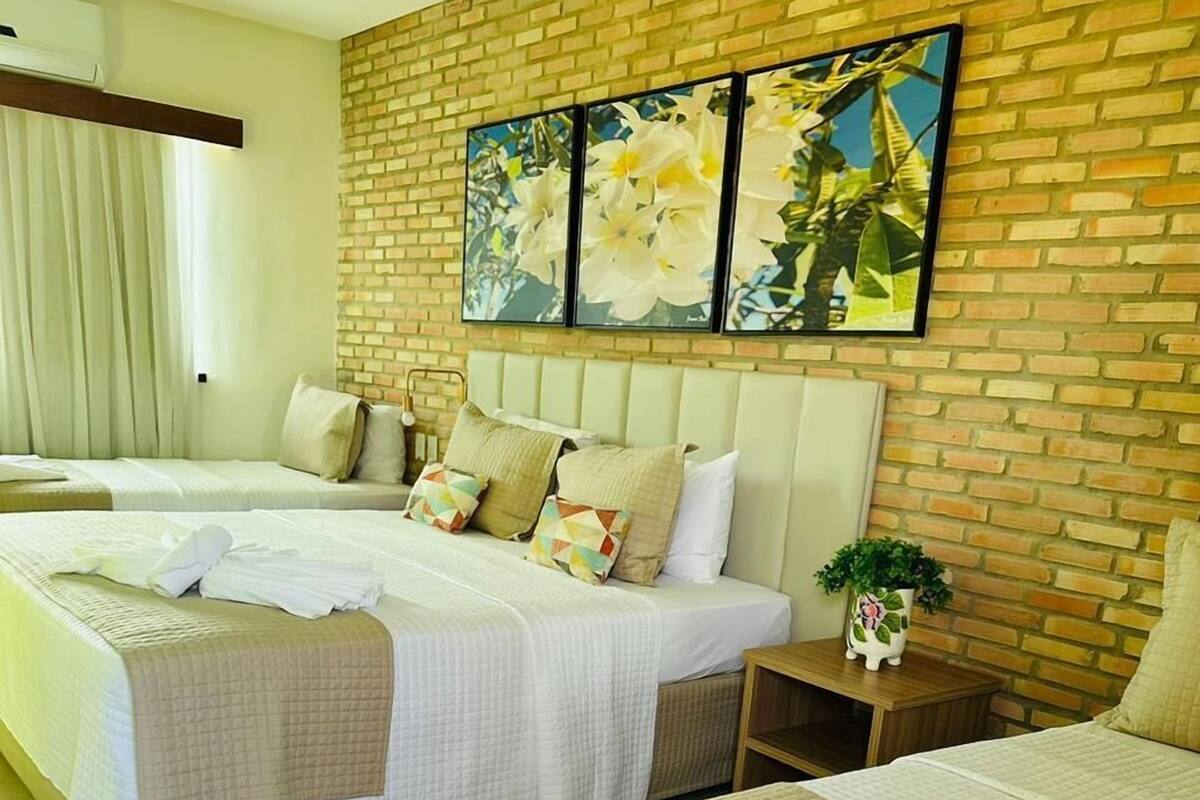 A hotel room with two beds, a brick wall, and a large floral painting.