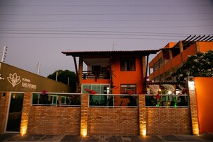 Un hotel con fachada de ladrillo, un balcón lleno de flores y un letrero que dice 