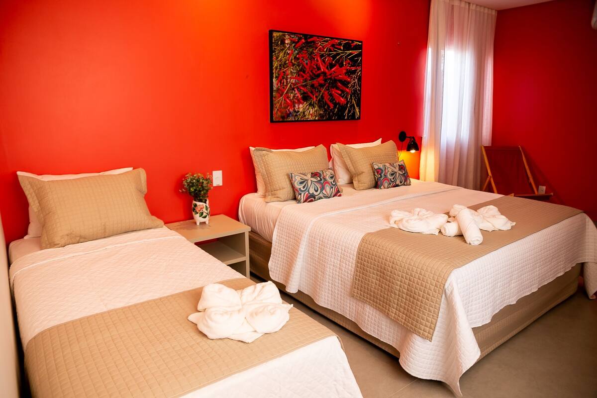 A hotel room with two beds, a painting on the wall, a nightstand, and a window with curtains.