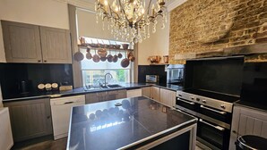 Une cuisine moderne dotée d’un îlot central, d’appareils électroménagers en acier inoxydable et d’un mur en briques.