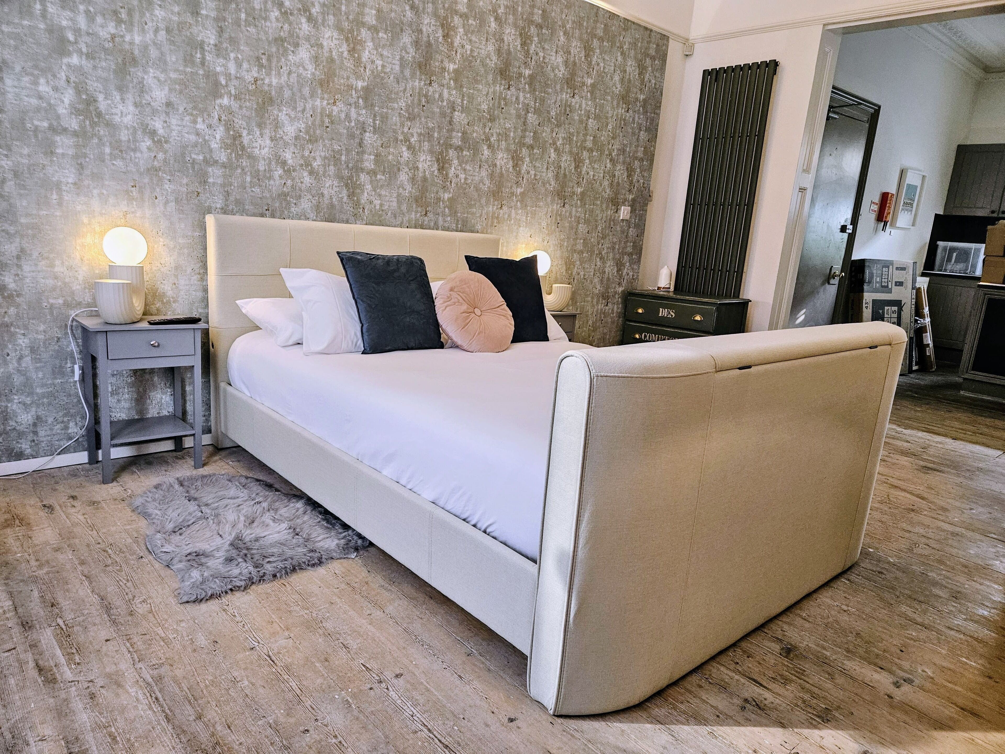 Een moderne slaapkamer met een groot bed, nachtkastjes, een vloerkleed en een kledingkast.