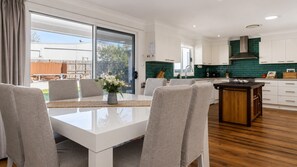 A modern kitchen with white cabinets, a green backsplash, and a wooden island.