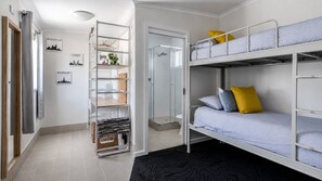A compact room with a bunk bed, a shelving unit, and a shower area. - A Wave from it All- Escape to Paradise (Berrara)