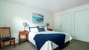 A bedroom with a bed, two bedside tables, a chair, a painting, and a wardrobe. - The Yellow Door Inverloch (Inverloch)
