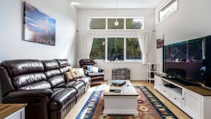 A living room with a leather sofa, a coffee table, a TV, and a bookshelf. - The Yellow Door Inverloch (Inverloch)