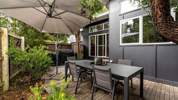 A patio with a table and chairs, a grill, and a large umbrella. - The Yellow Door Inverloch (Inverloch)