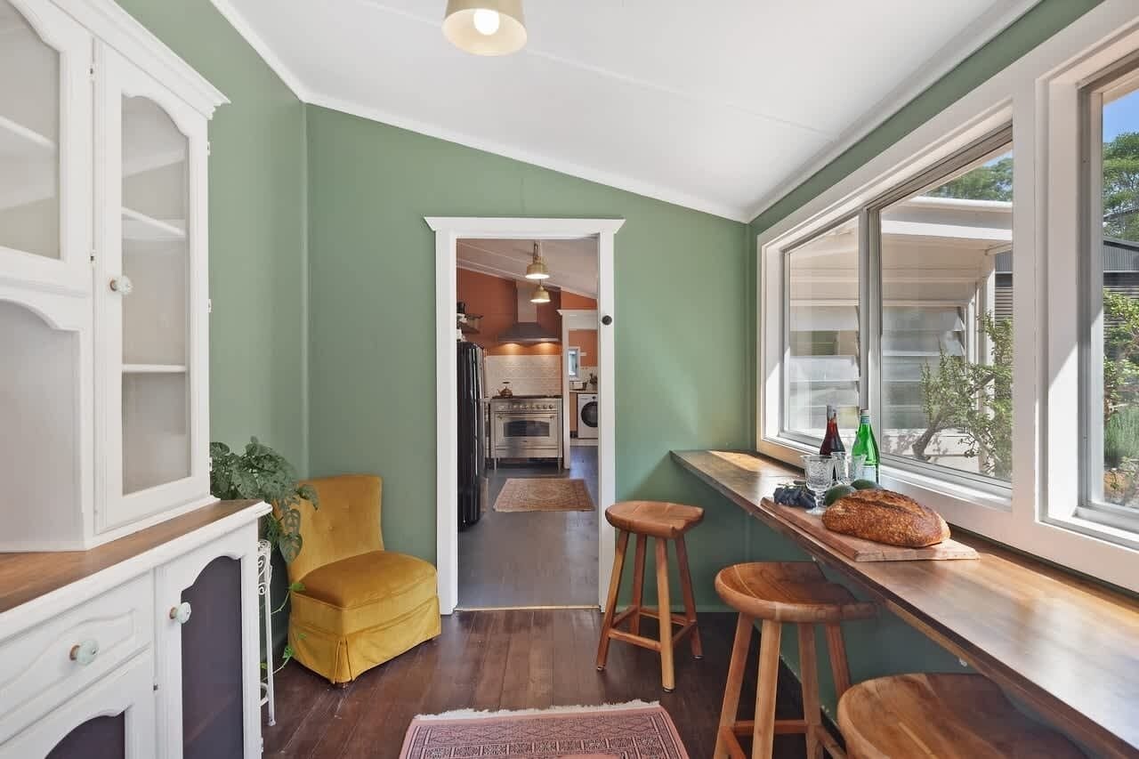 A kitchen with a wooden countertop, stools, and a window with a view of the outside.