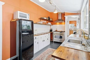 A compact kitchen with a refrigerator, stove, sink, and cabinets. - Luxe Farm Stay: Animals, Fire Pit, Beach (Wamberal)