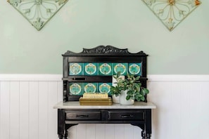 A black wooden table with a white countertop, decorated with a potted plant and a stack of books. - Luxe Farm Stay: Animals, Fire Pit, Beach (Wamberal)