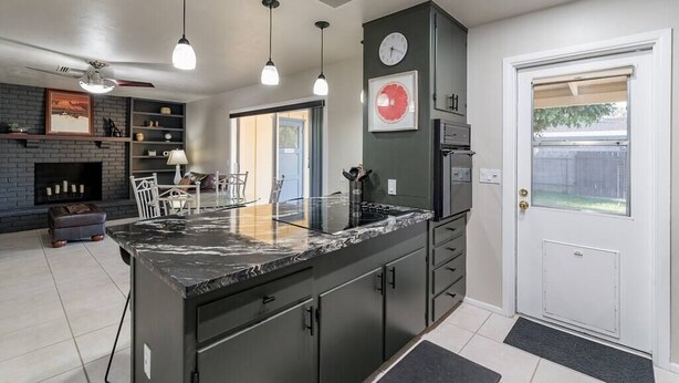 Une cuisine moderne dotée d’un îlot central, de luminaires suspendus et d’une horloge intégrée.