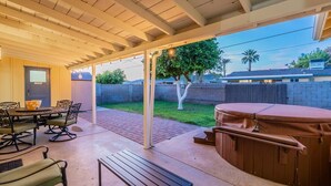 Une terrasse extérieure dotée d’un espace salon couvert, d’un jacuzzi et d’un barbecue.