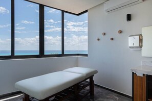 A room with a bench, a wall-mounted air conditioner, and a view of the ocean.