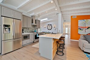 Una cocina moderna con electrodomésticos de acero inoxidable, una isla grande y un comedor con vistas.