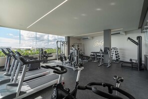 A gym with cardio machines, free weights, and a wall with a neon sign.
