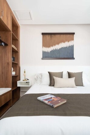 A bedroom with a bed, a nightstand, a wooden wardrobe, and a wall-mounted artwork.