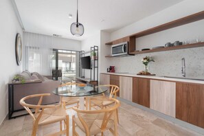 A modern kitchen with a round glass table and wooden chairs, a built-in microwave, and a wooden countertop.