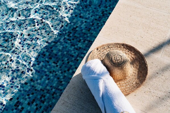 A poolside setting with a woven straw hat and a white towel.