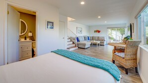 Une pièce moderne et bien éclairée, comprenant un lit, un canapé, une table à manger et un fauteuil en osier.