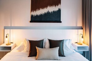 Una habitación de hotel con una cama, dos mesitas de noche y una obra de arte colgada en la pared.