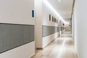 Un pasillo largo y estrecho con suelo de baldosas y paredes blancas.