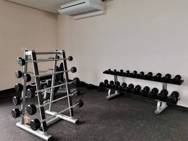 Une salle de sport équipée d’un support à squats et d’haltères.