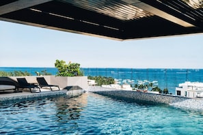 Une piscine à débordement offrant une vue imprenable sur l’océan, surmontée d’une structure architecturale moderne.
