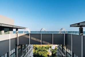 A modern building with a rooftop terrace overlooking a body of water.