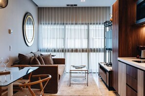 A modern living room with a sofa, coffee table, and a dining area with chairs.