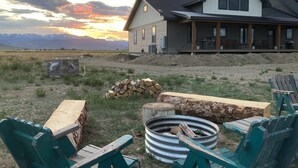 A house with a large porch, a fire pit, and outdoor seating. - The Rendezvous - Mountain views surrounded by fields (Cody)