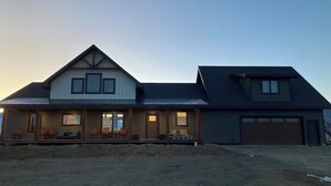 A two-story house with a front porch, a garage, and a well-lit driveway. - The Rendezvous - Mountain views surrounded by fields (Cody)