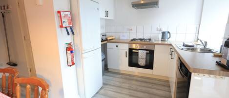 A modern kitchen with white cabinets, a stainless steel range hood, and a dishwasher.