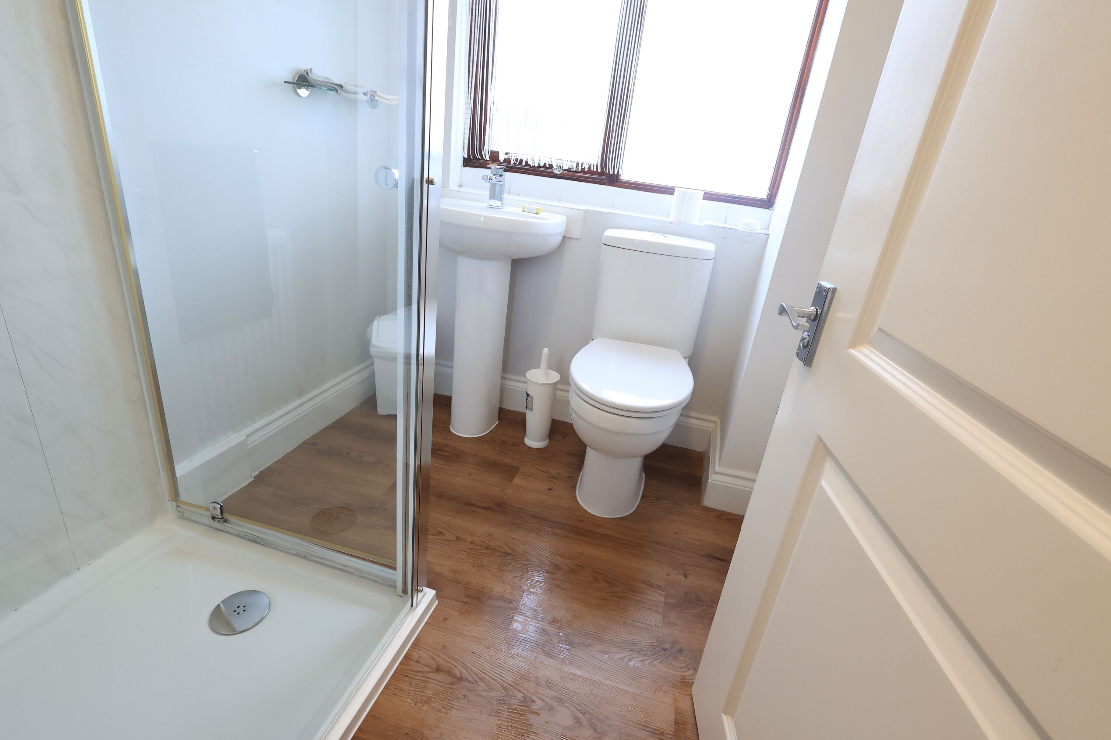 A bathroom with a glass shower enclosure, a white sink, and a toilet.