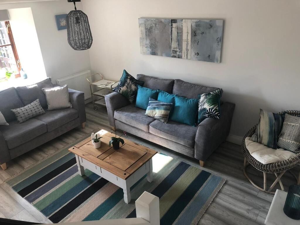 A living room with a grey sofa, a wooden coffee table, and a striped rug.