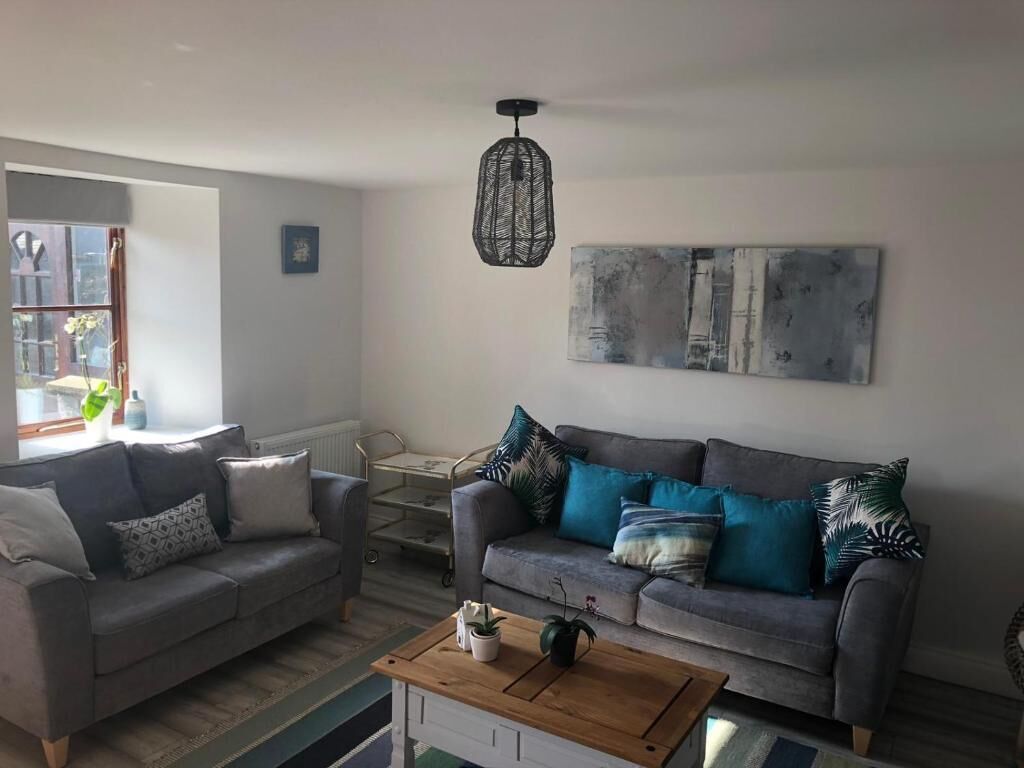 A living room with two sofas, a coffee table, and a hanging light fixture.