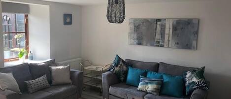A living room with two sofas, a coffee table, and a hanging light fixture.