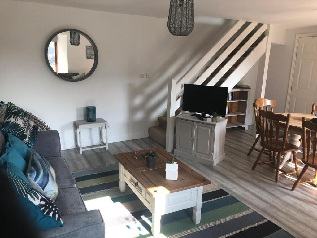 A living room with a sofa, coffee table, TV, and a staircase.