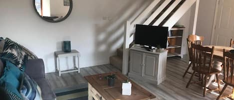 A living room with a sofa, coffee table, TV, and a staircase.